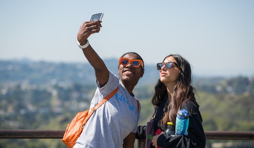 Two students taking a selfie while on an outing. Both are wearing sunglasses and smiling.
